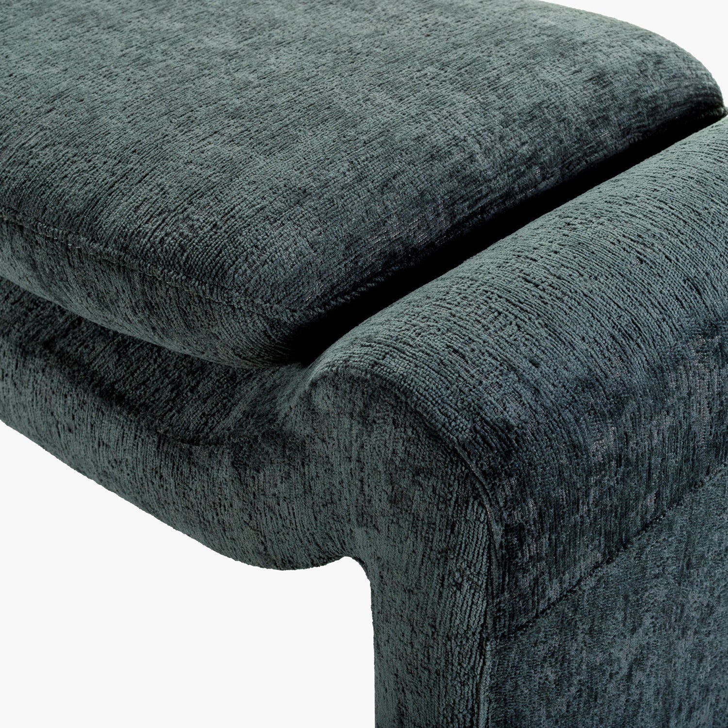 Close-up of a textured dark teal upholstered chair corner on a white background