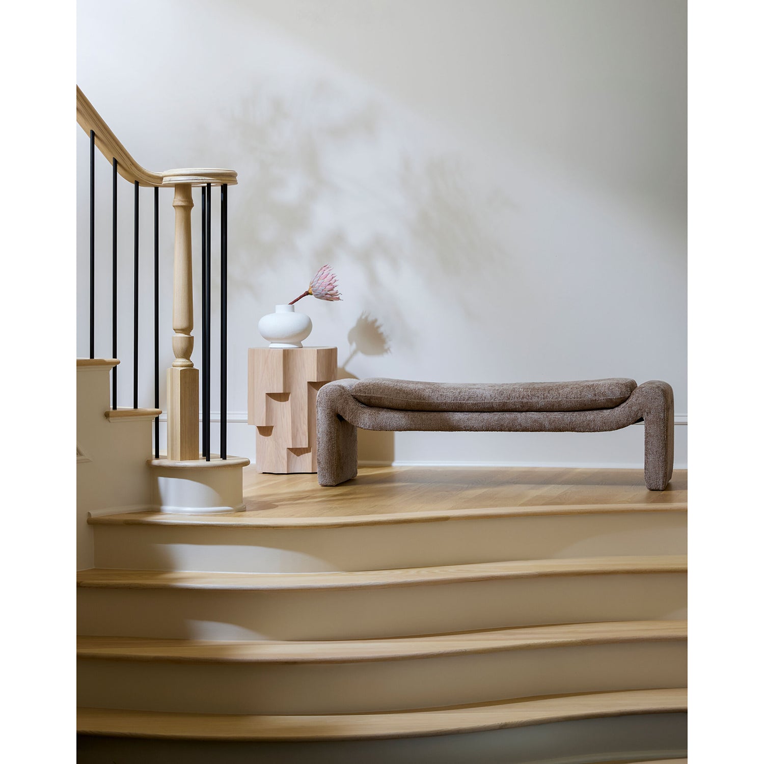 Staircase with a modern bench and decorative vase in a minimalistic setting