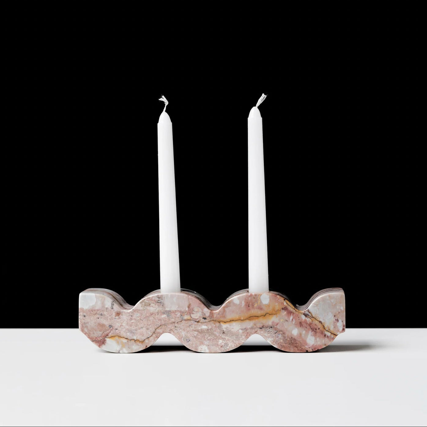 Marble candle holder with two white candles on a black background