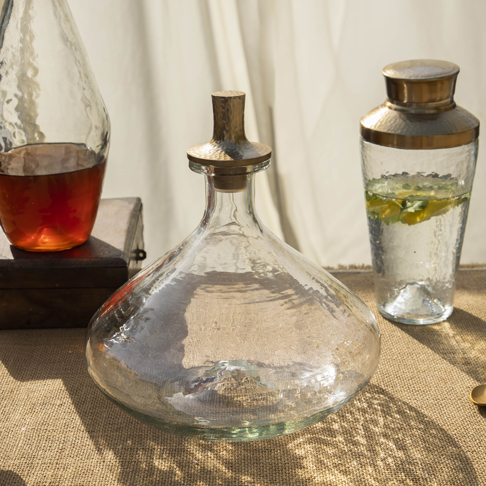 Clear glass decanter with bronze stopper on a textured surface