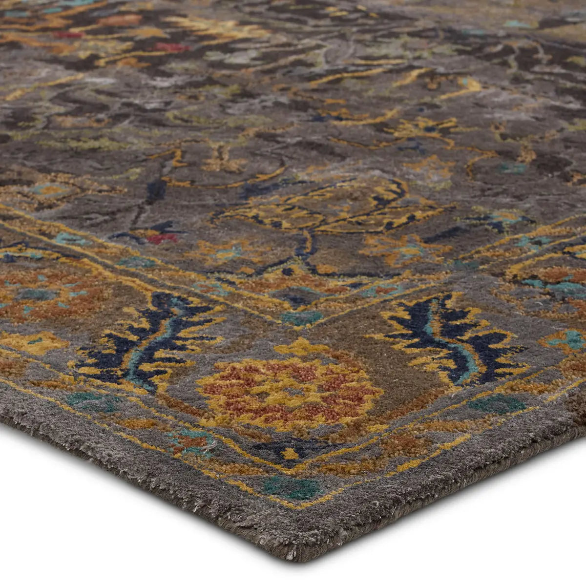 A close-up image of a textured rug with a floral pattern in muted colors including gray, green, gold, and turquoise.