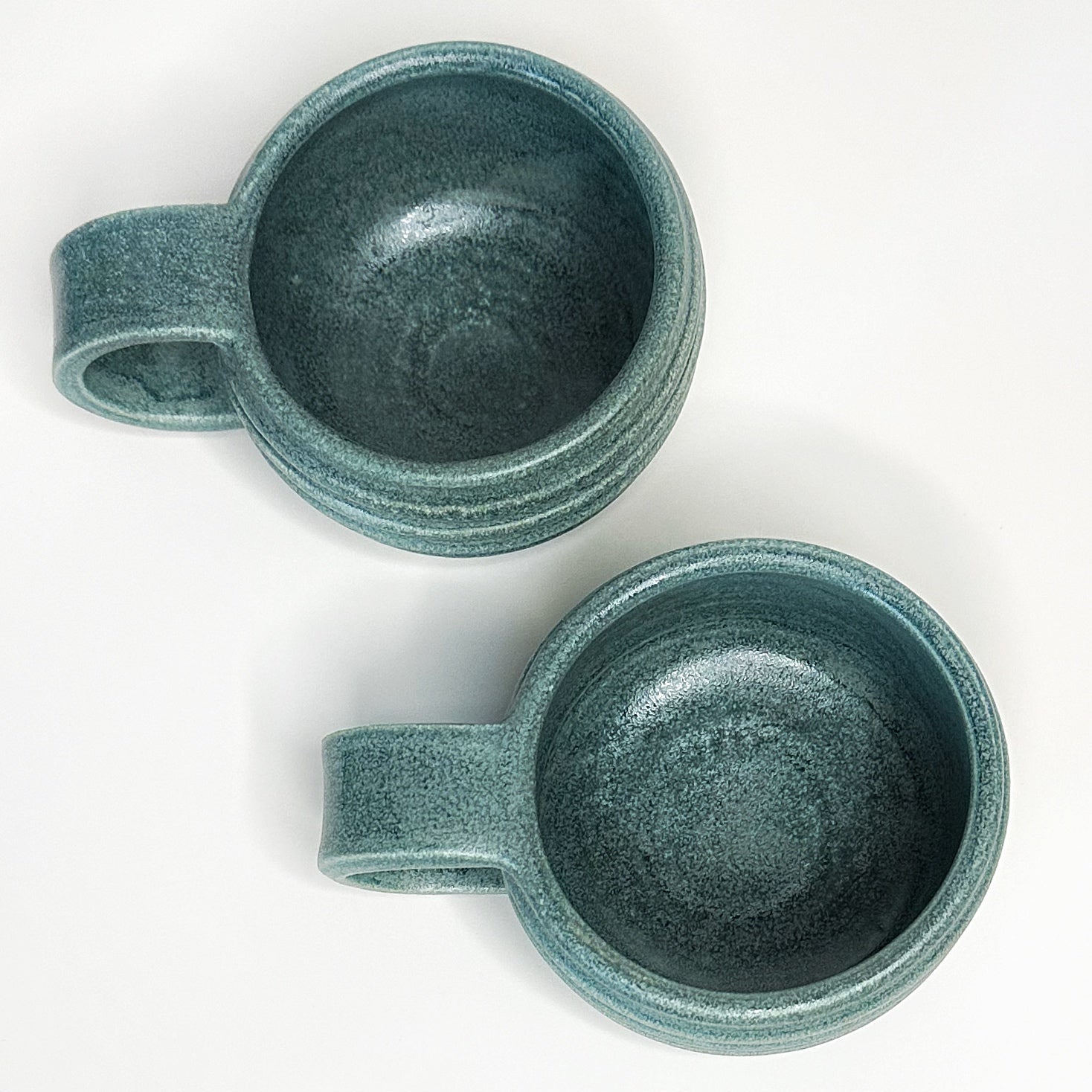 Two green ceramic mugs on a white background