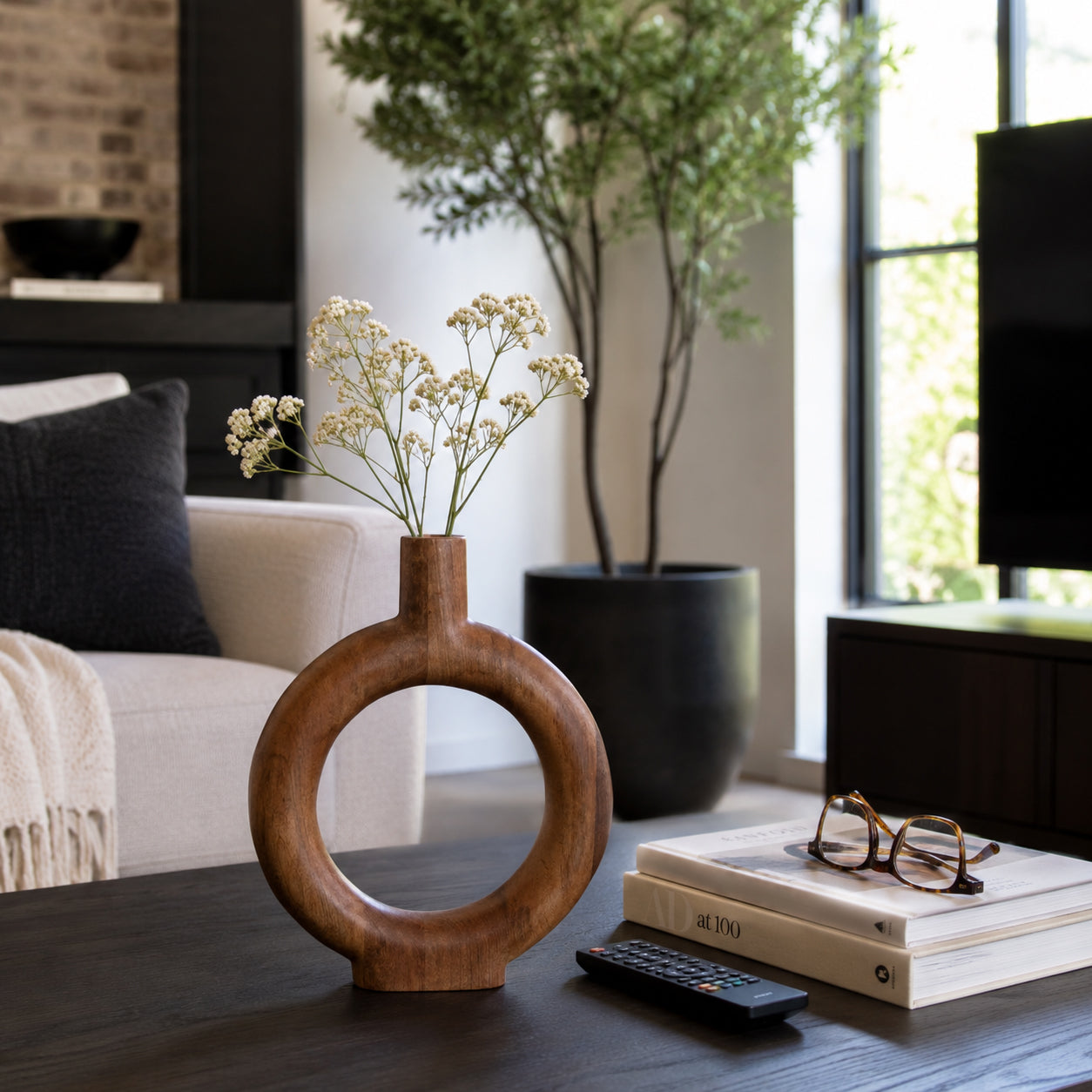 Wooden vase with dried flowers on a coffee table in a living room.