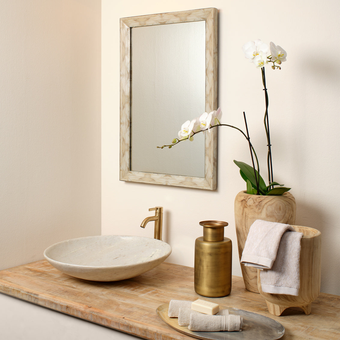 Bathroom setup with a sink, mirror, and decorative elements on a wooden surface.