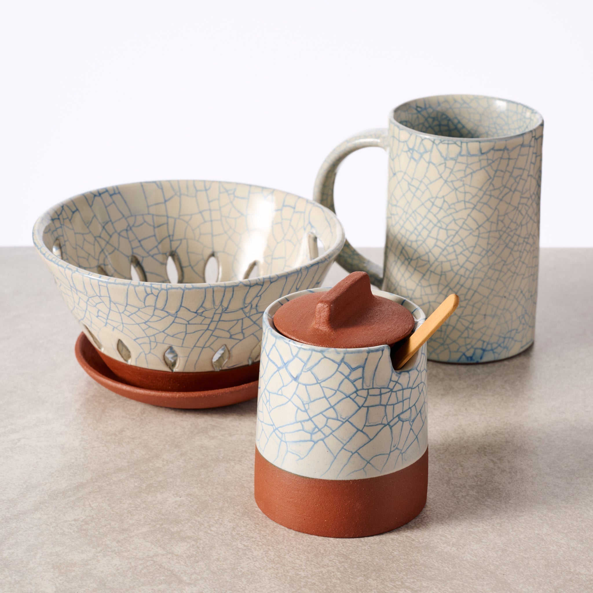 Set of ceramic bowls and mugs with a cracked pattern on a neutral background