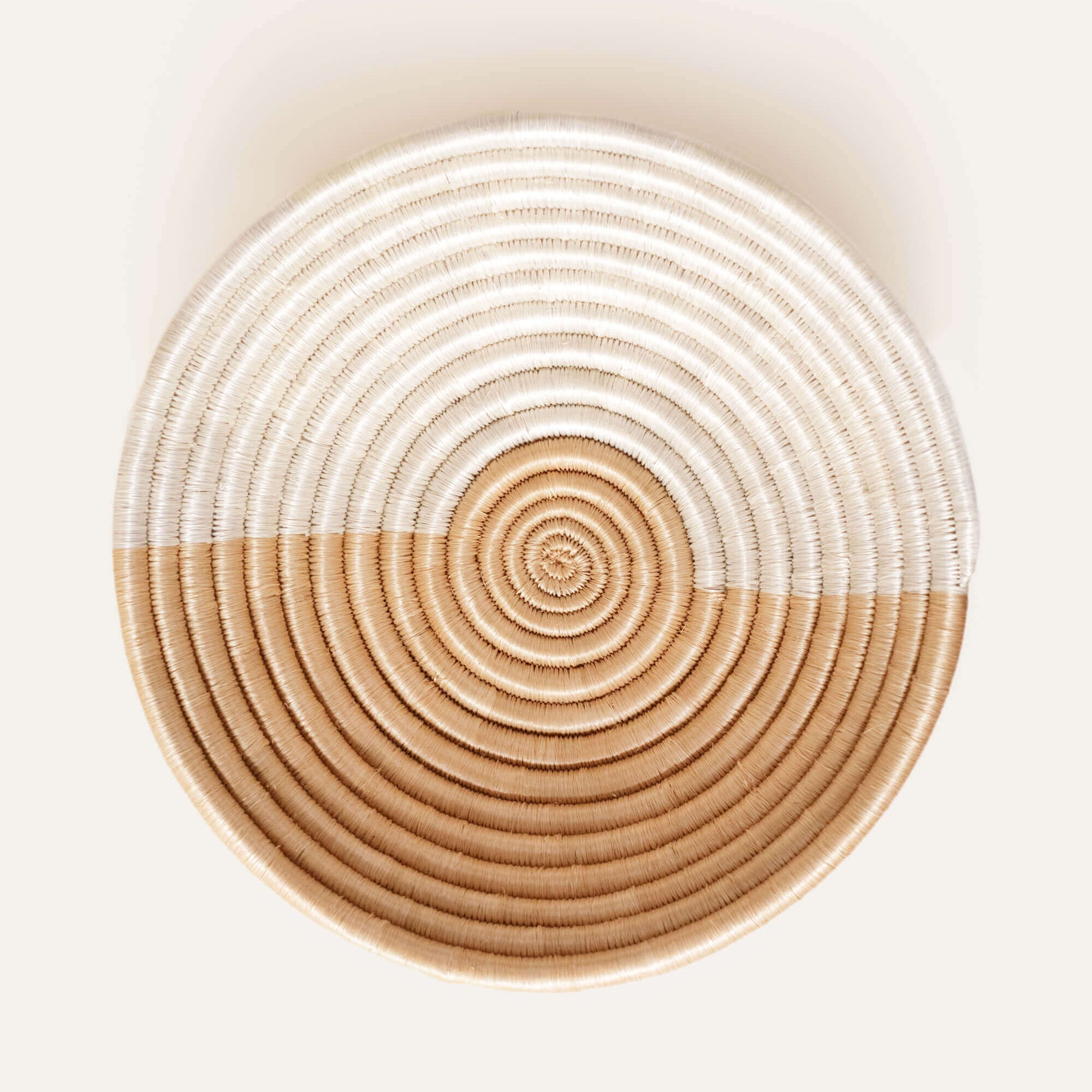 Round woven basket with concentric circle pattern on a white background