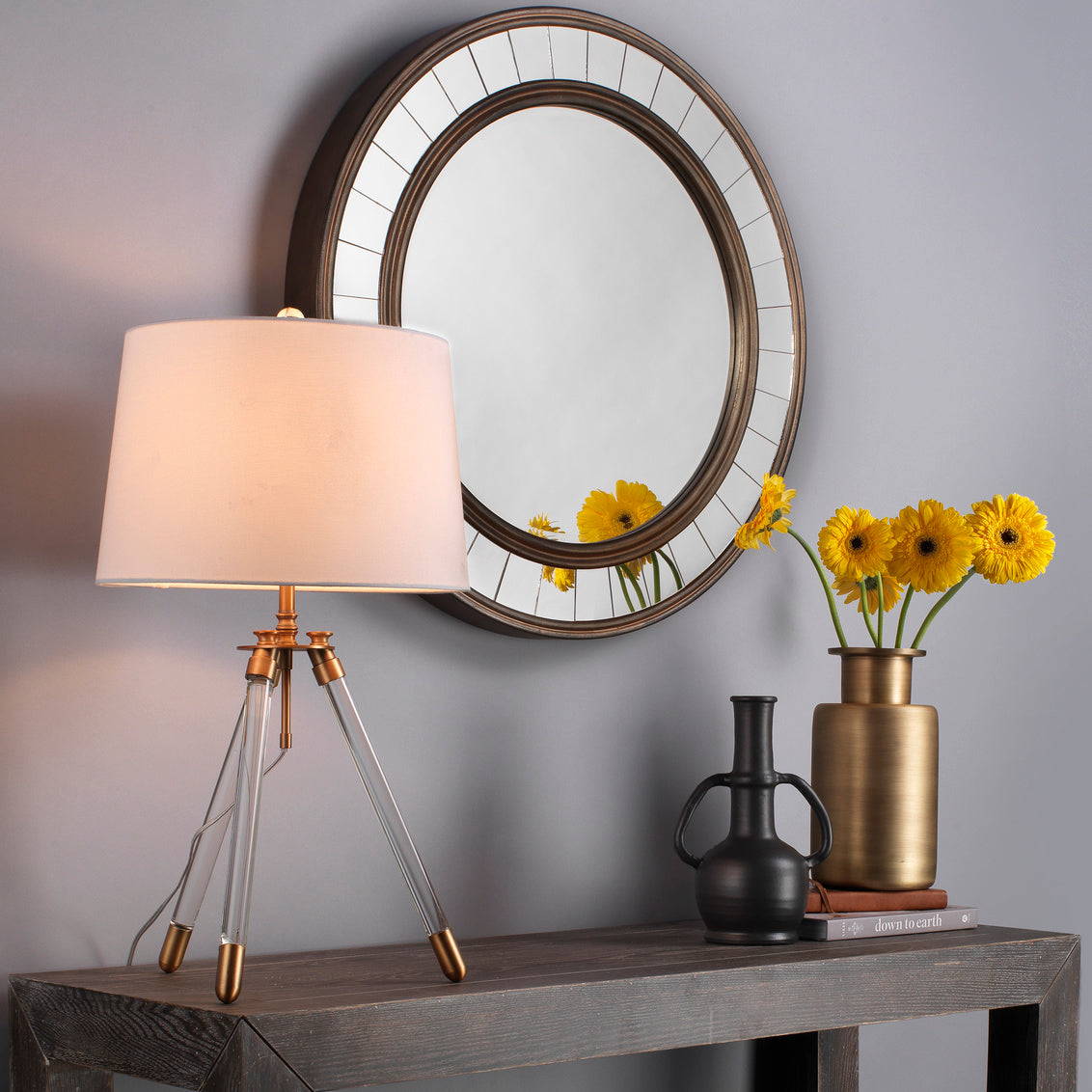 Decorative table with lamp, mirror, and vases against a gray wall