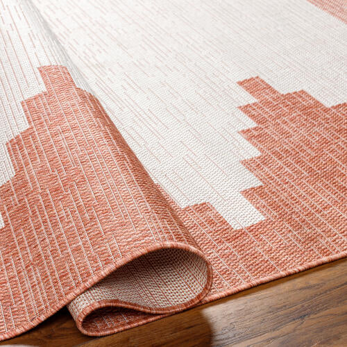 Pink and white geometric patterned rug on a wooden floor