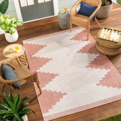 Patterned rug on a wooden floor with chairs and plants