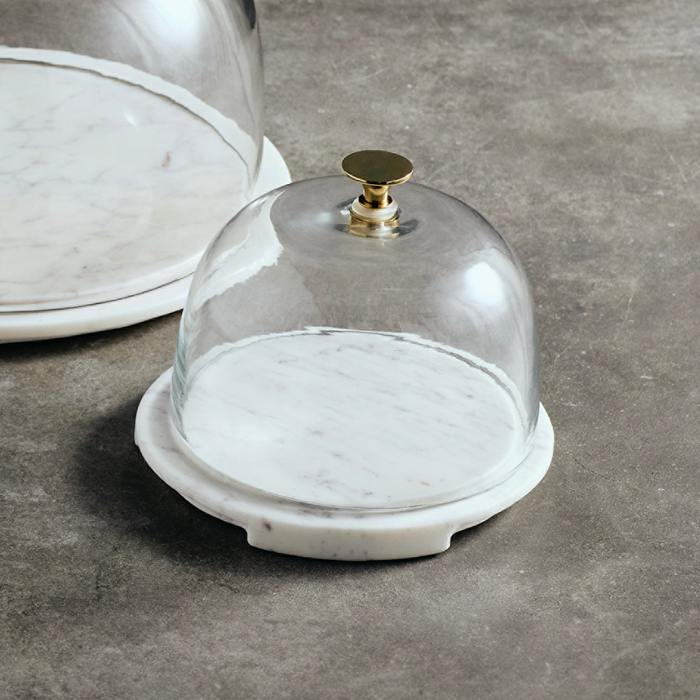 Glass serving dome with marble base on a gray surface