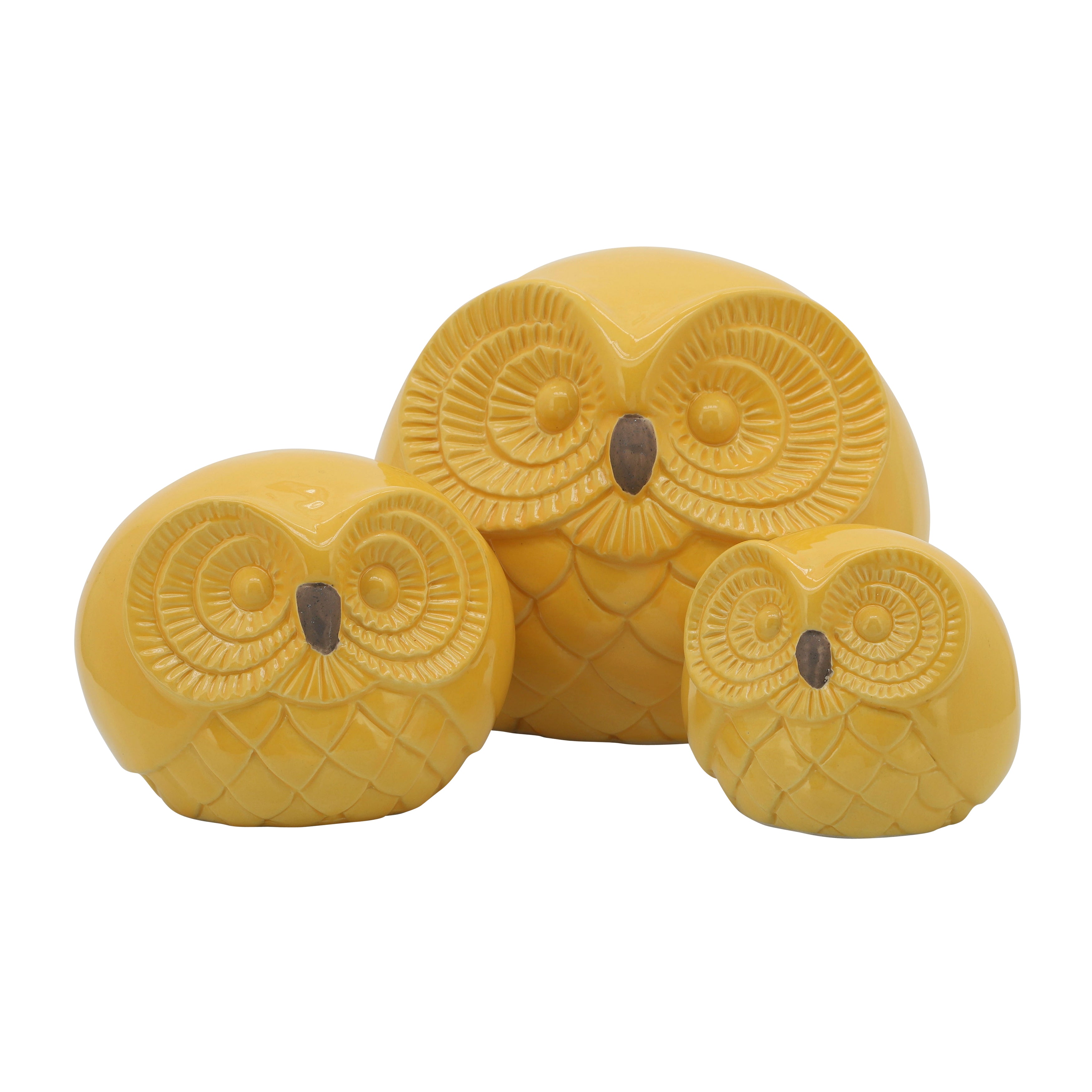 Set of three yellow owl-shaped candles on a white background