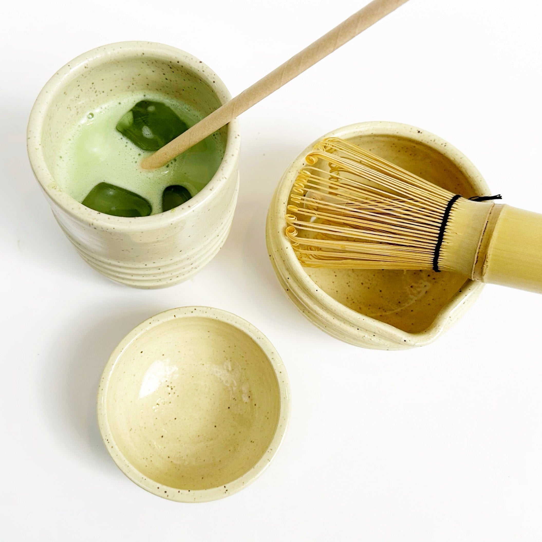 Matcha green tea preparation set with a bowl, whisk, and scoop on a white background