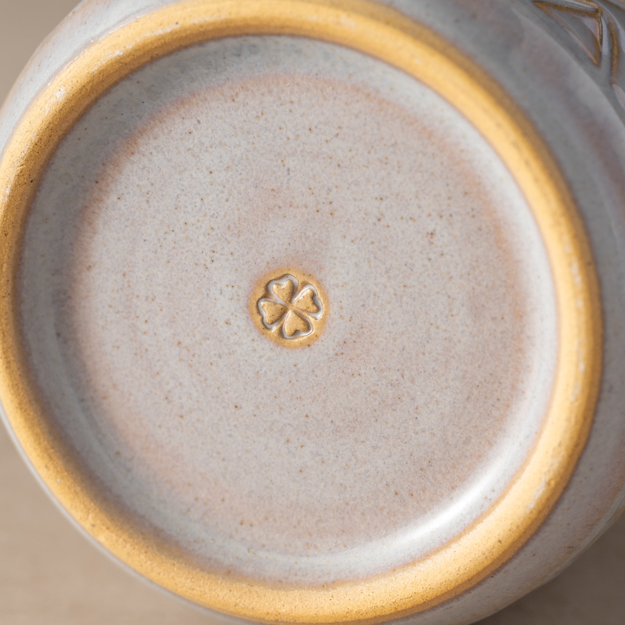 Close-up of a ceramic dish with a gold rim and a central clover design.