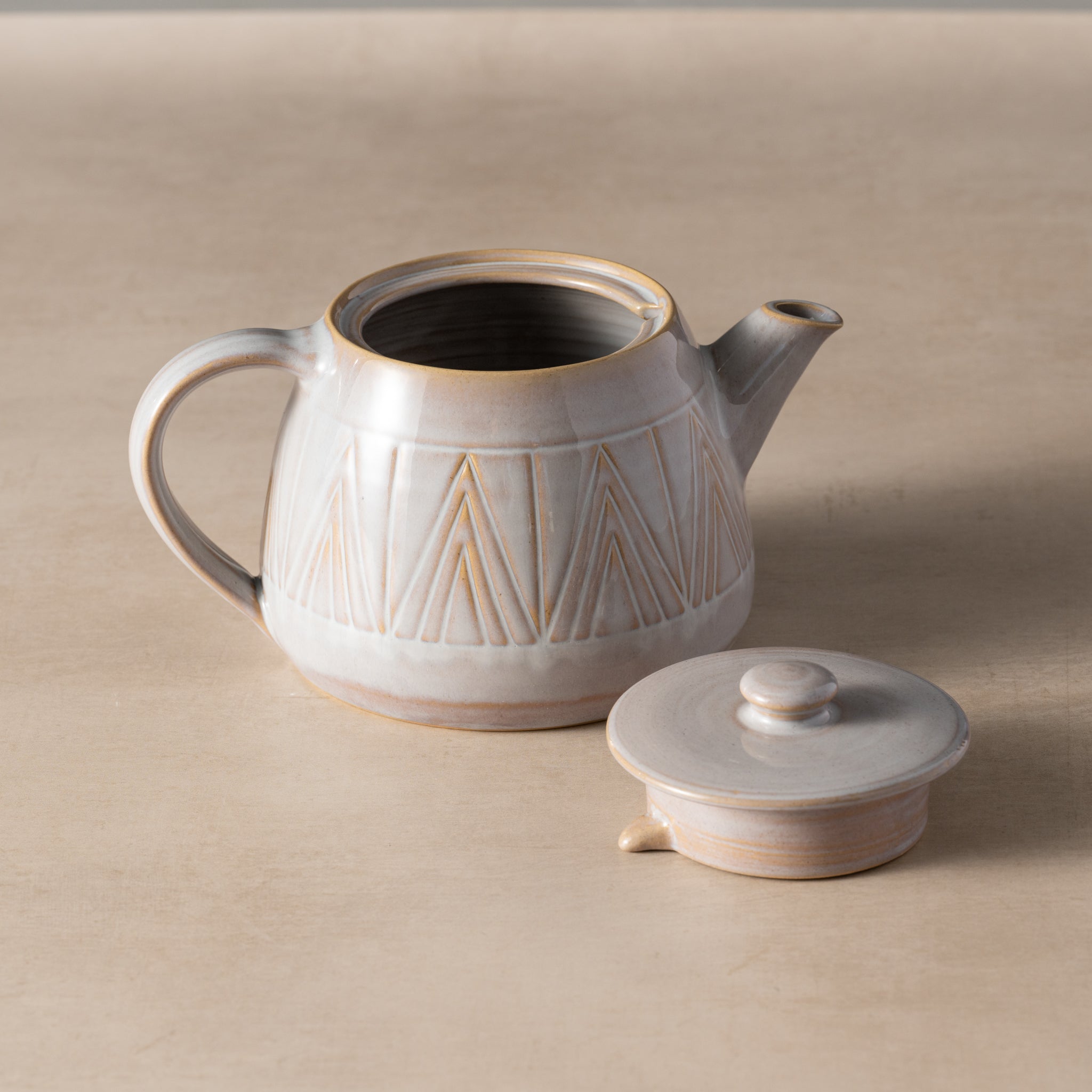 Ceramic teapot with geometric design on a beige background