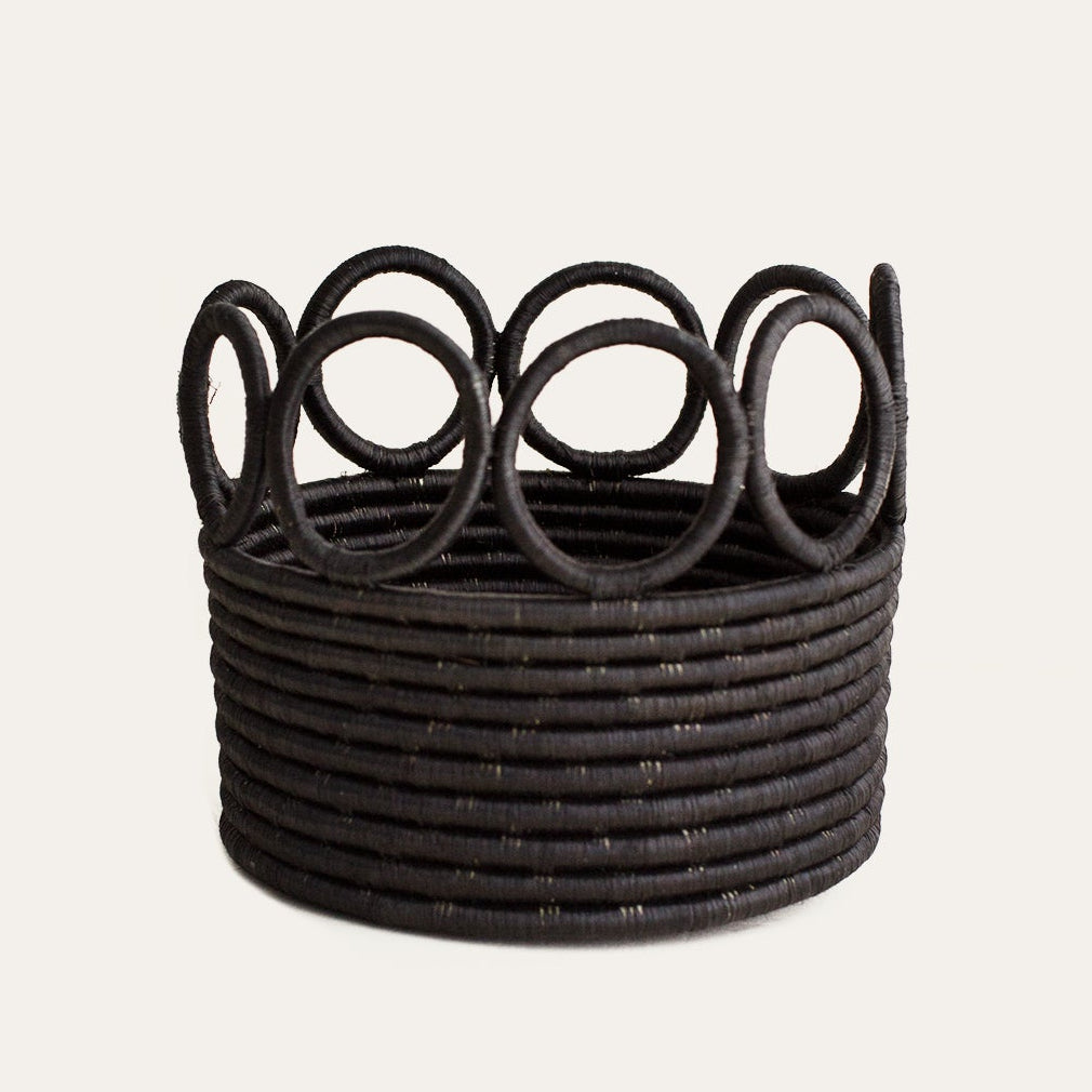 Black woven basket with circular patterns on a light gray background