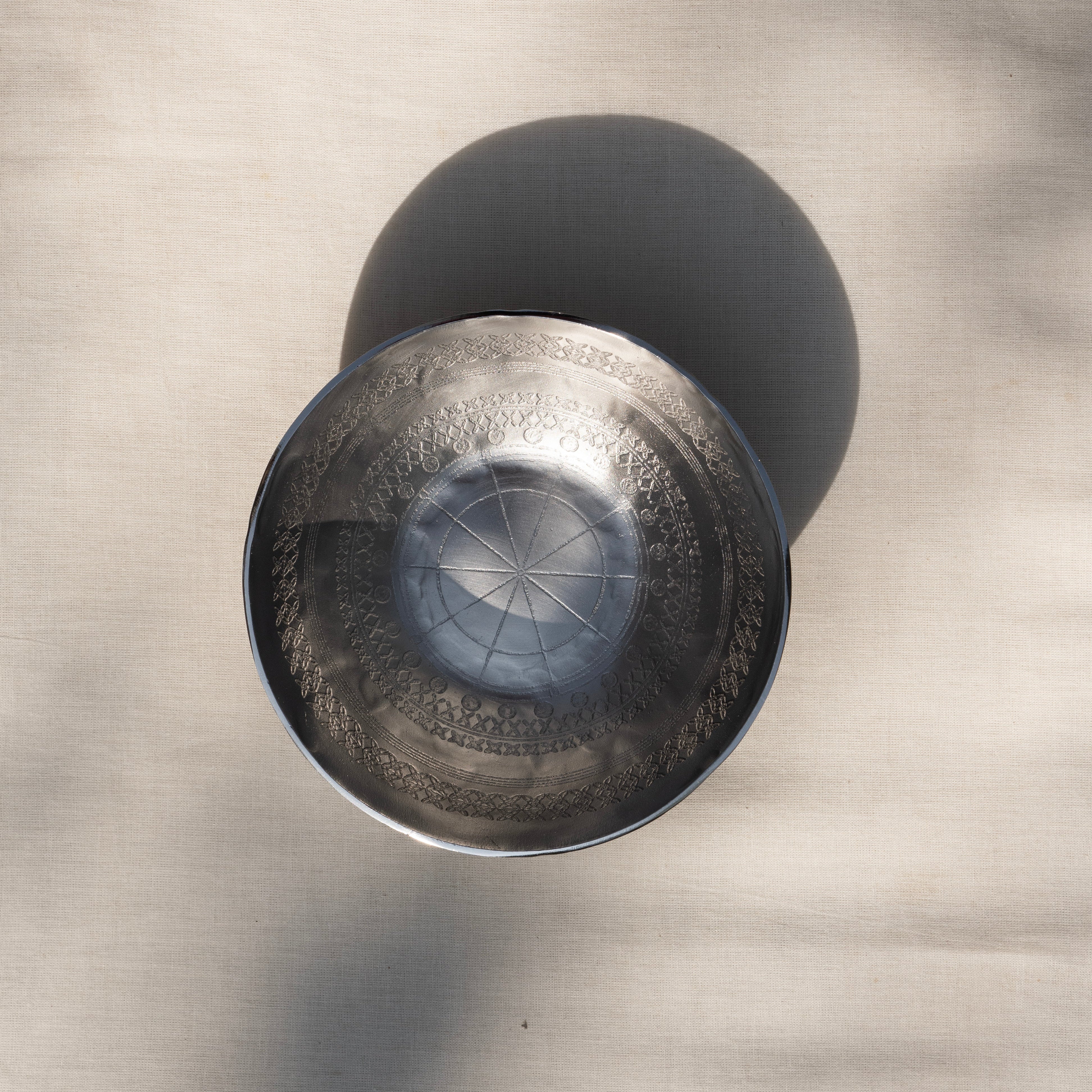 Metallic bowl with intricate design on a textured surface