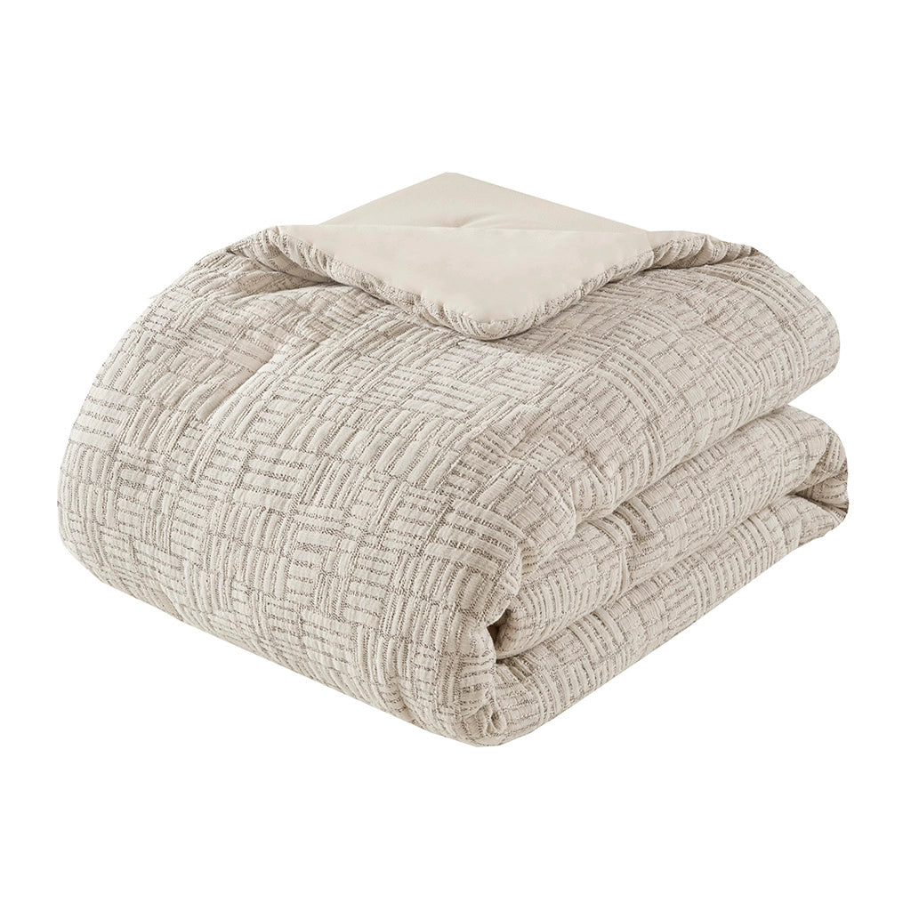 Folded beige textured comforter on a white background