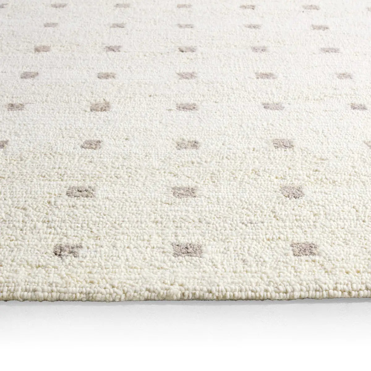 Close-up of a textured white rug with subtle pattern on a light background