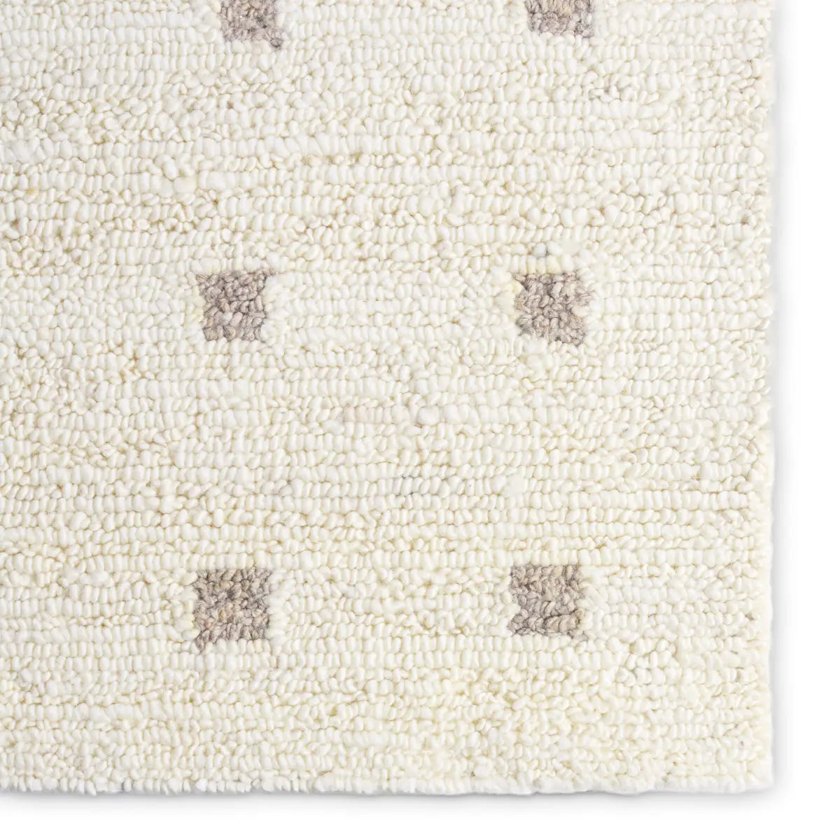 Close-up of a textured white rug with brown square patterns