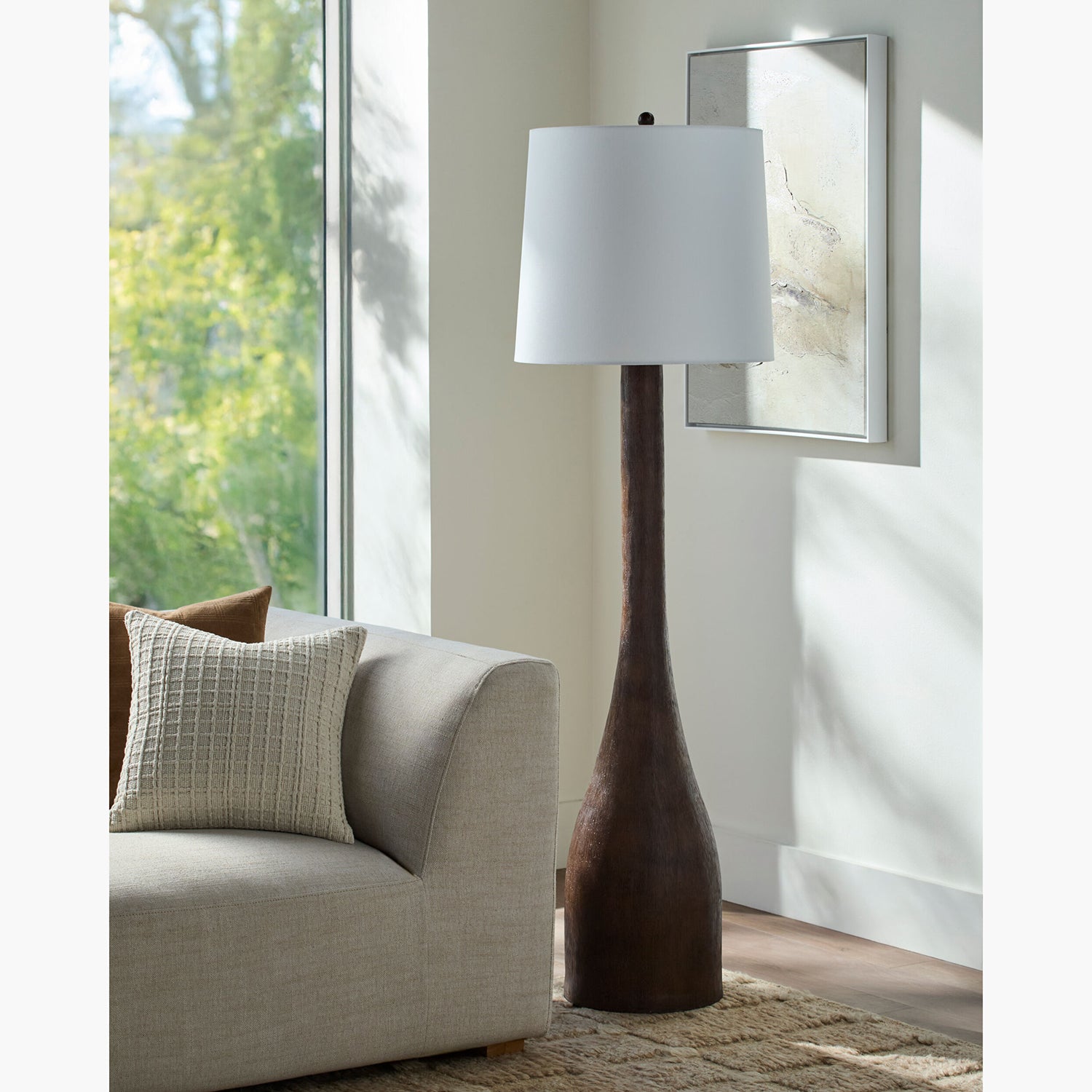 Tall floor lamp with a white shade in a living room setting.