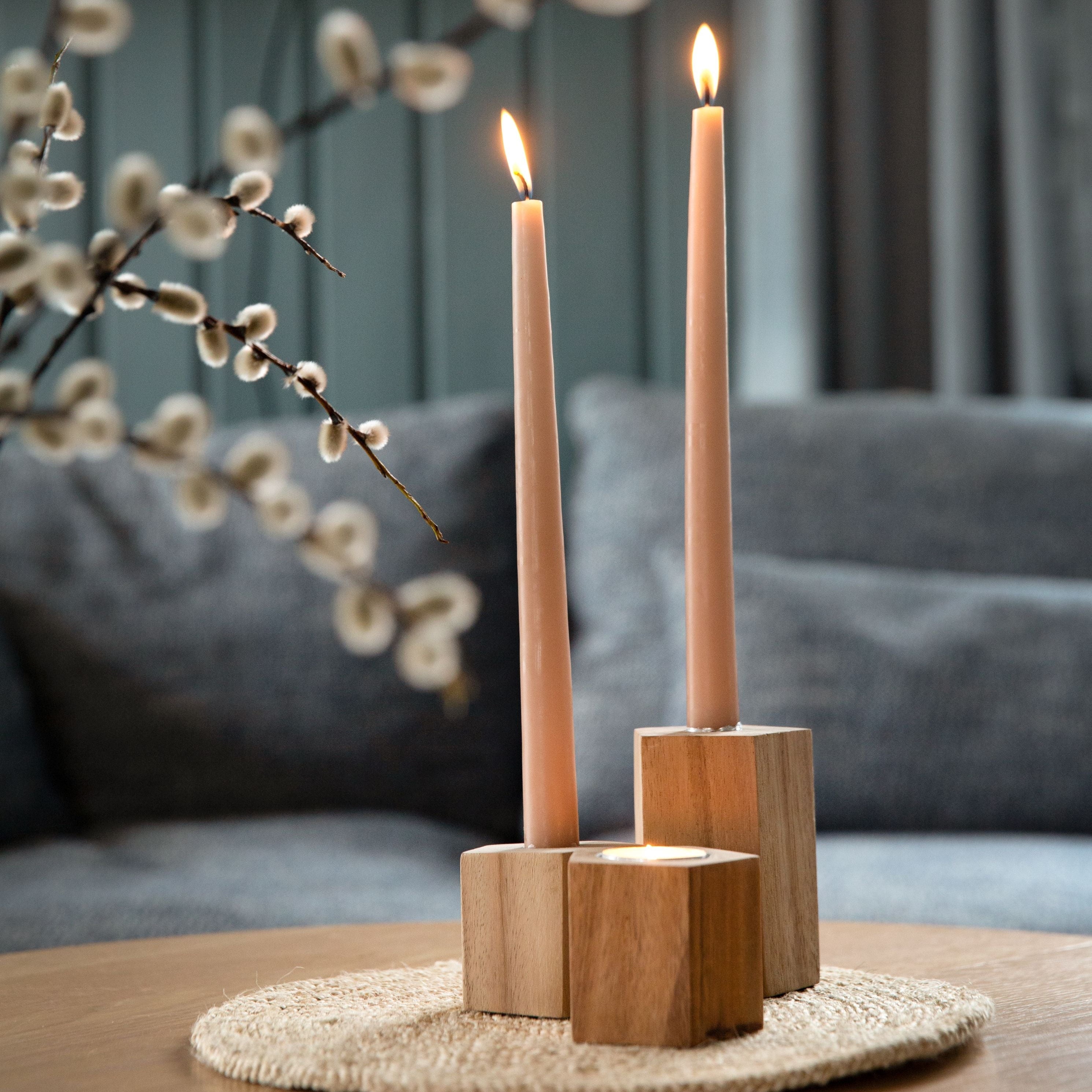 Wooden candle holder with two lit candles on a table with a blurred background