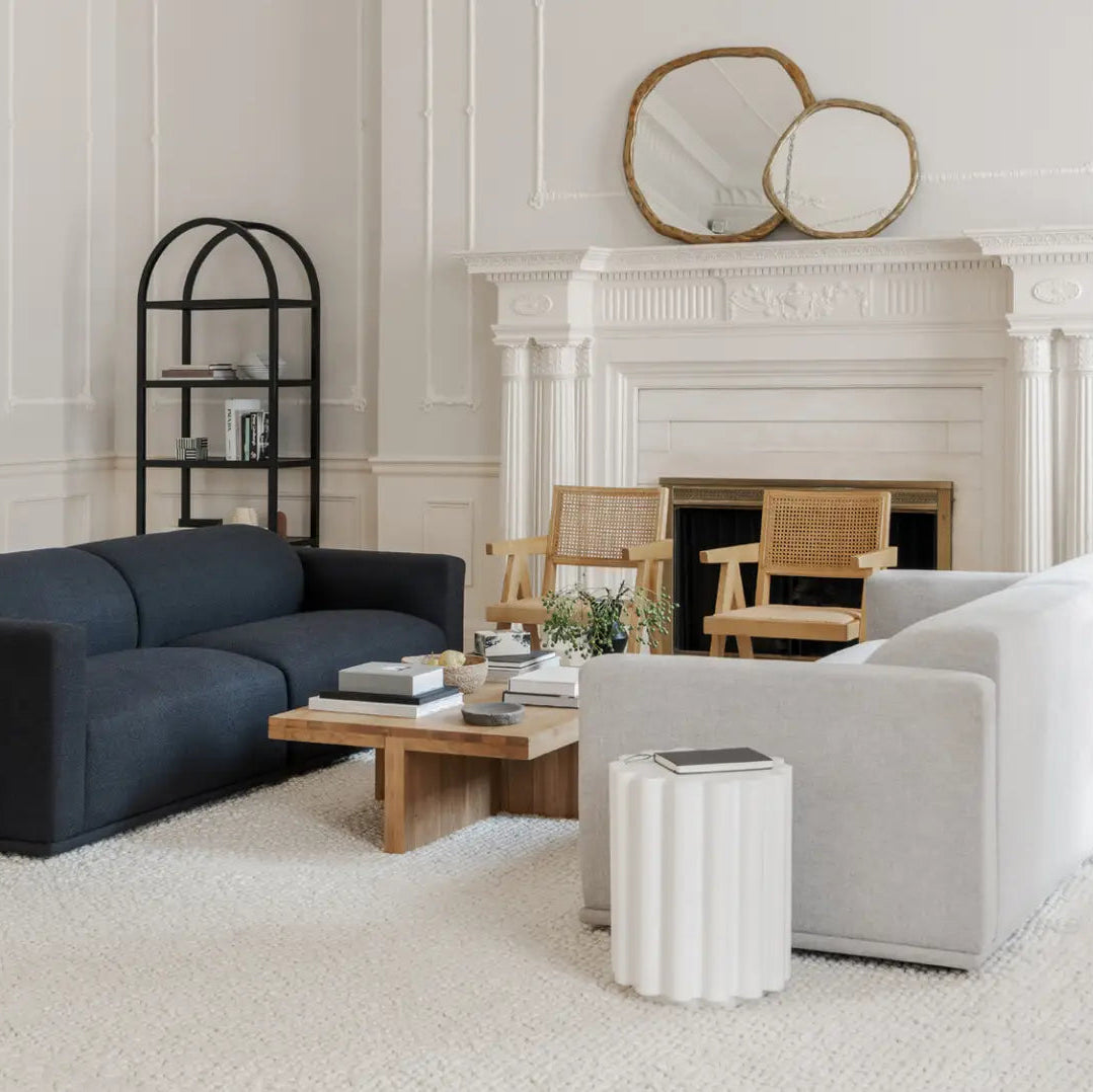 Modern living room with a navy sofa, white armchair, and decorative items.