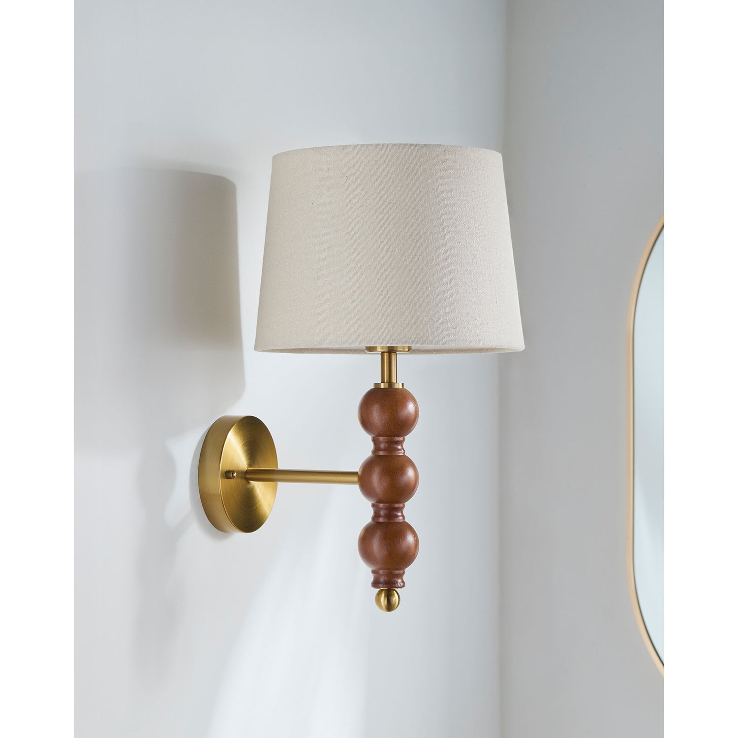 Wall-mounted lamp with wooden and brass design on a light gray wall.