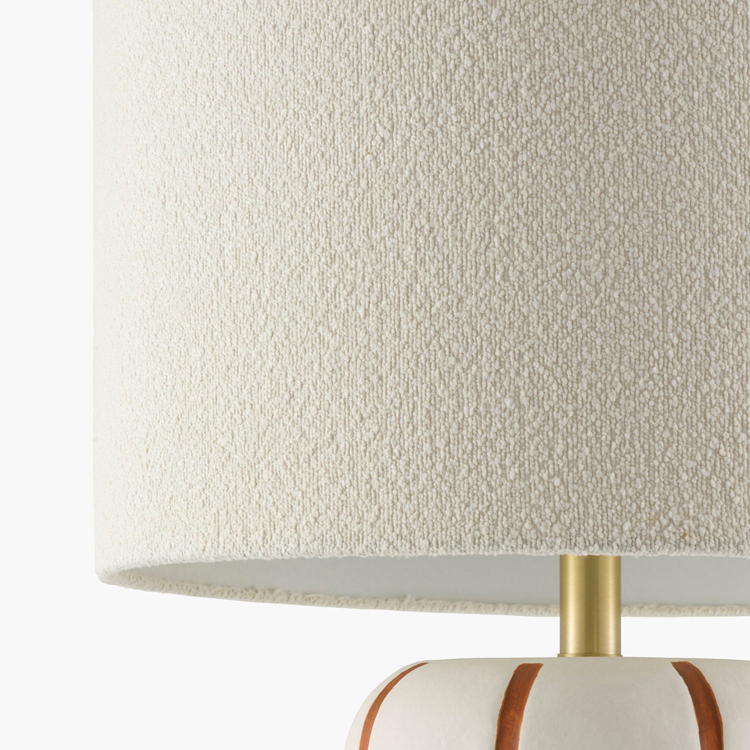 Close-up of a textured lampshade with a gold neck on a white background