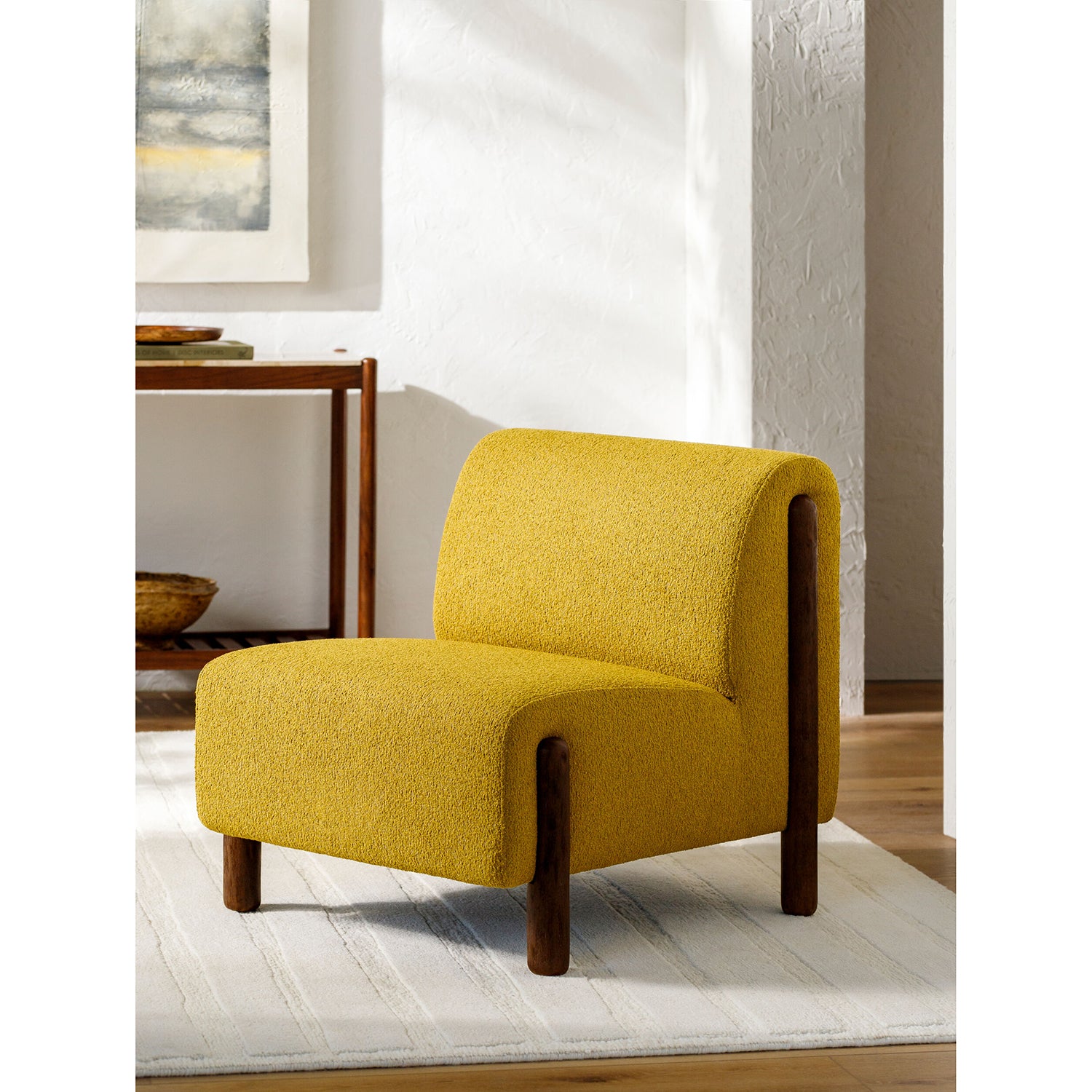 Yellow armchair in a room with a table and artwork on the wall.