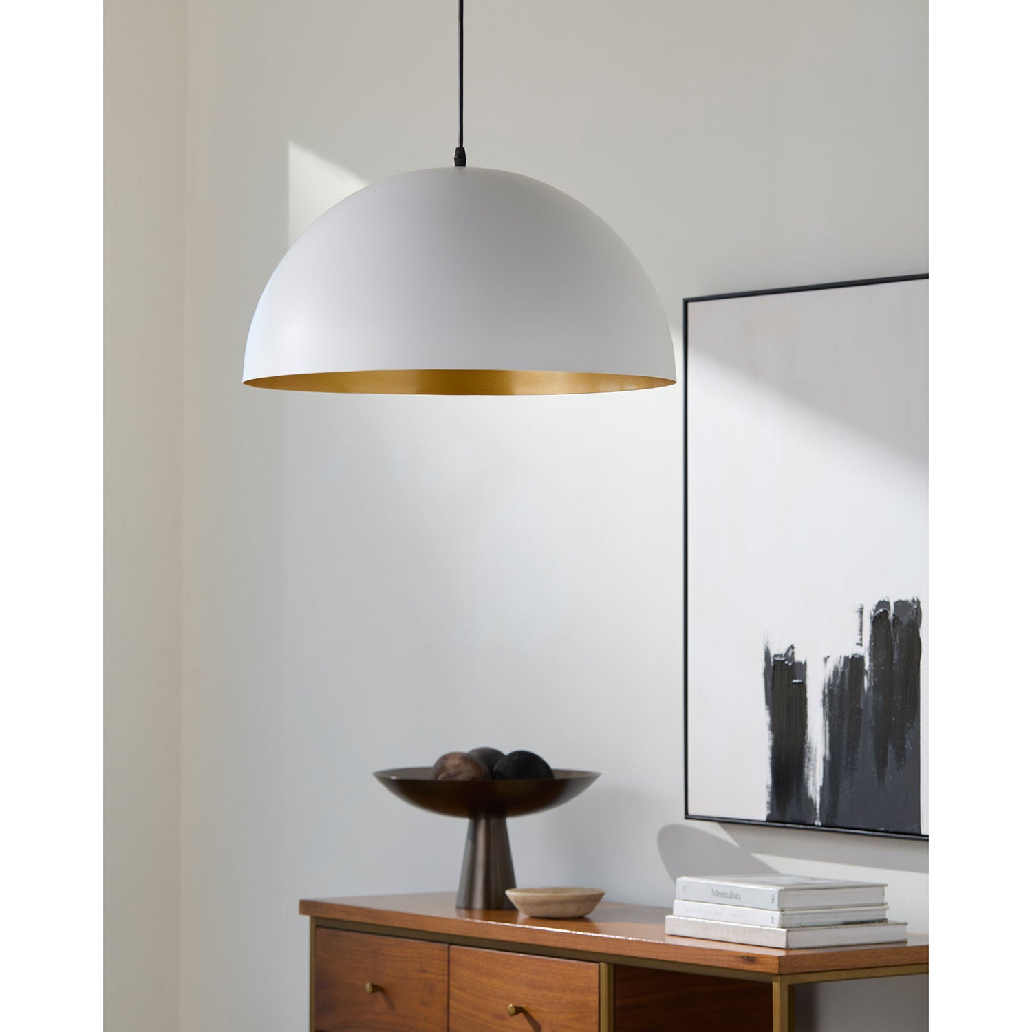 White pendant light hanging above a wooden side table with decor items.
