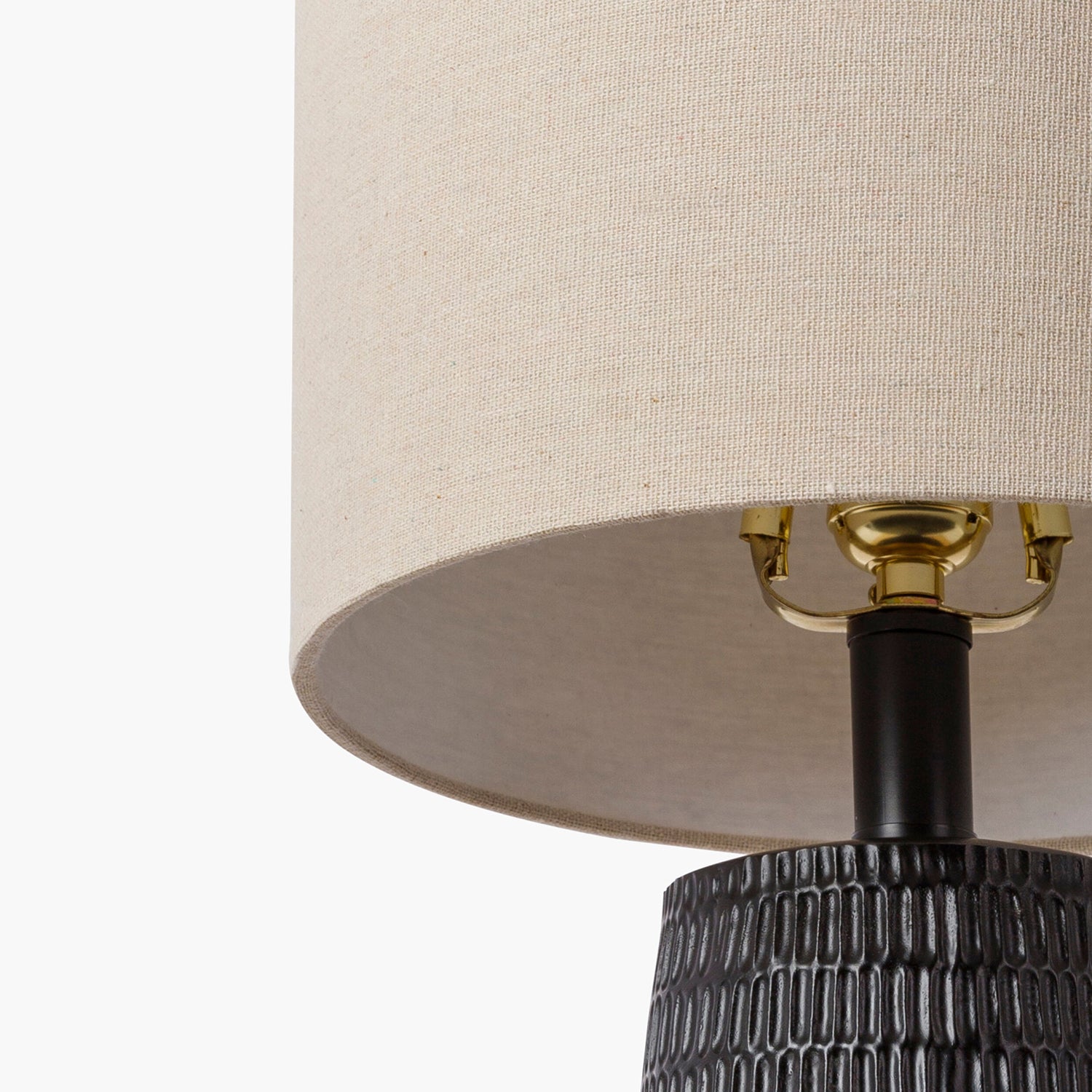 Close-up of a lamp with a beige shade and textured black base on a white background