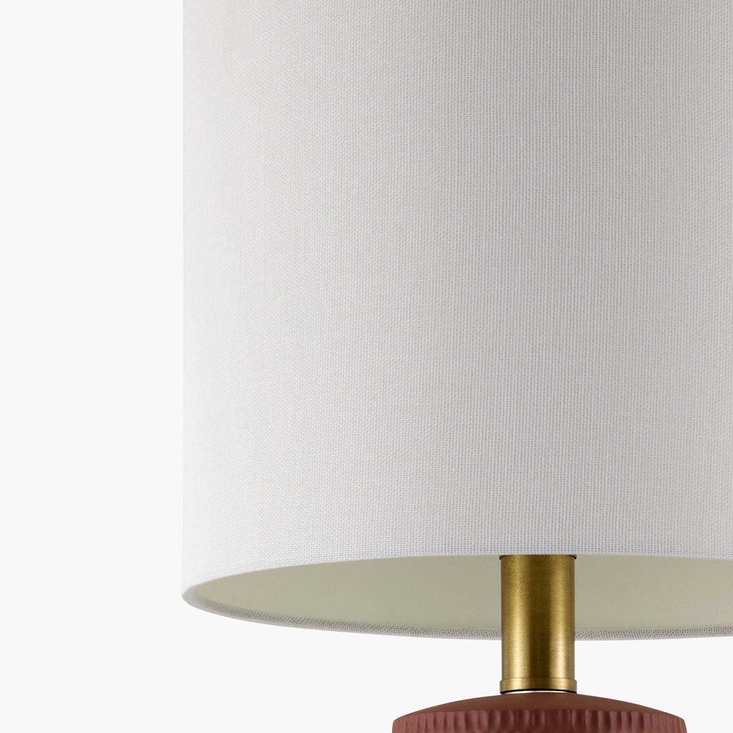 Lamp with a white shade and gold and red base on a white background