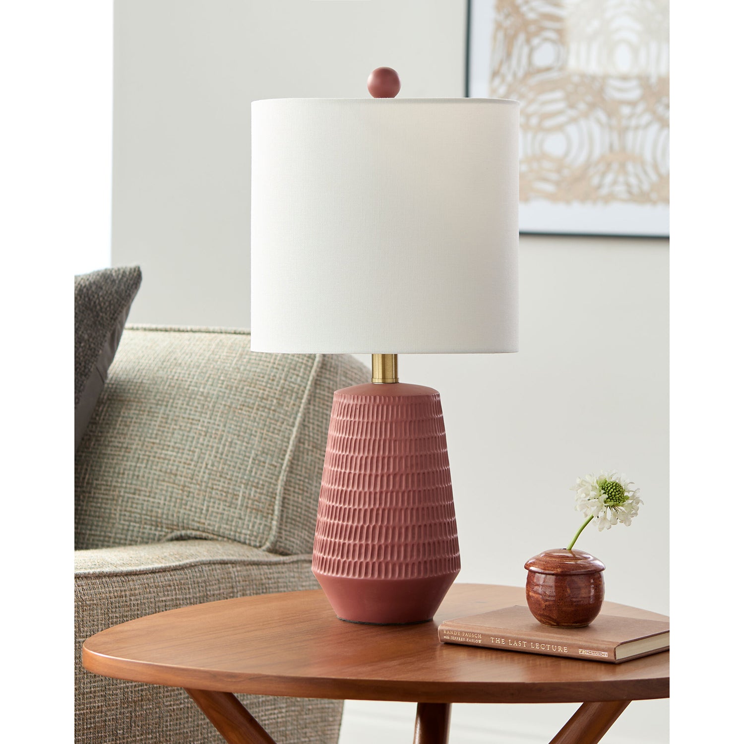 Brick textured table lamp with white shade on a wooden table in a living room setting.
