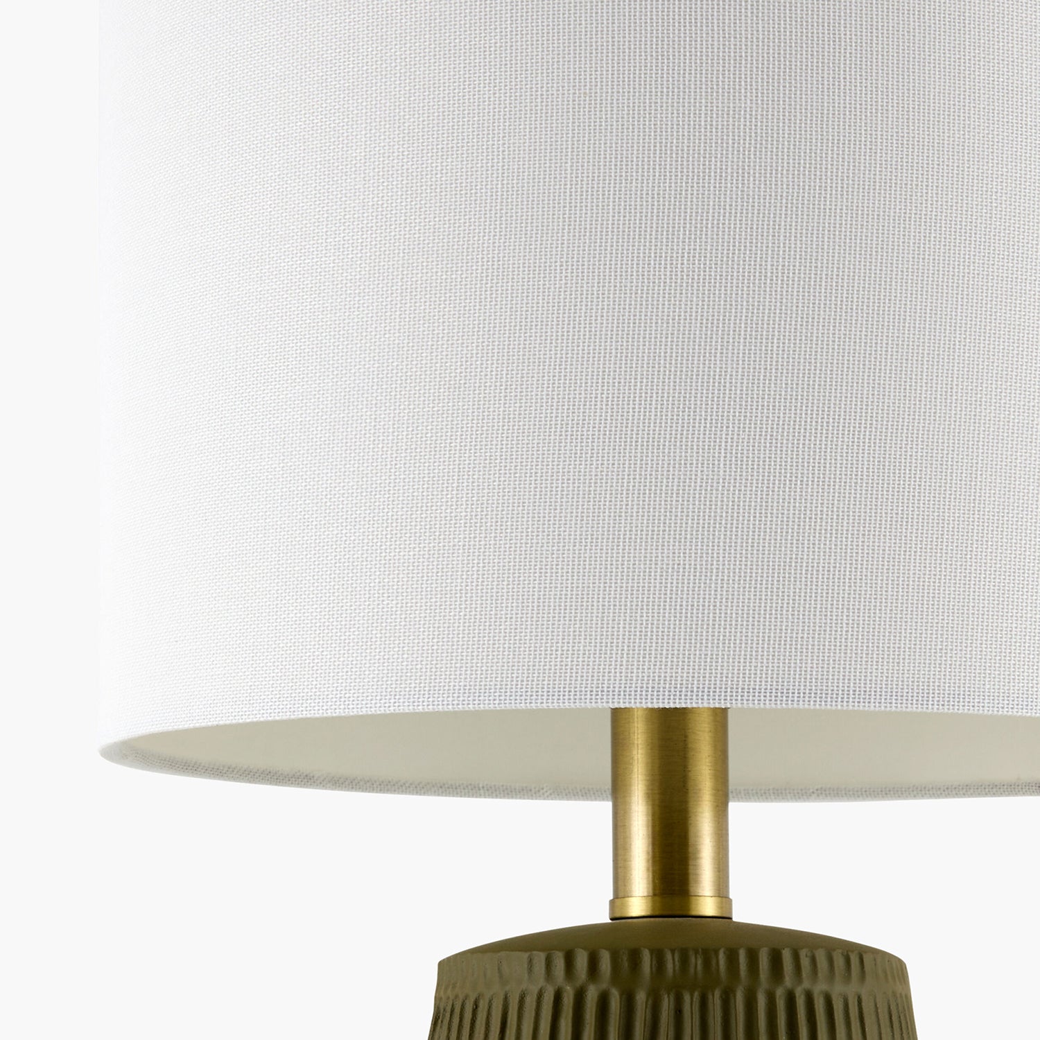 Close-up of a lamp with a white shade and gold neck with a green base on a white background