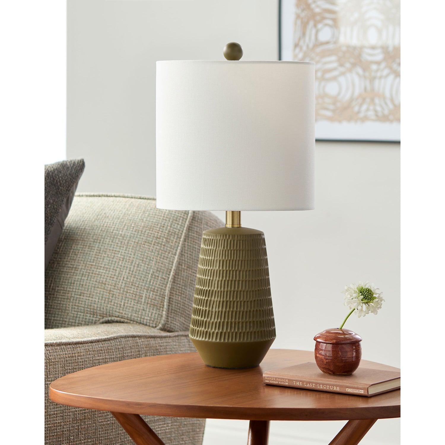 Table lamp with ribbed green base and white shade on a wooden table in a living room setting.