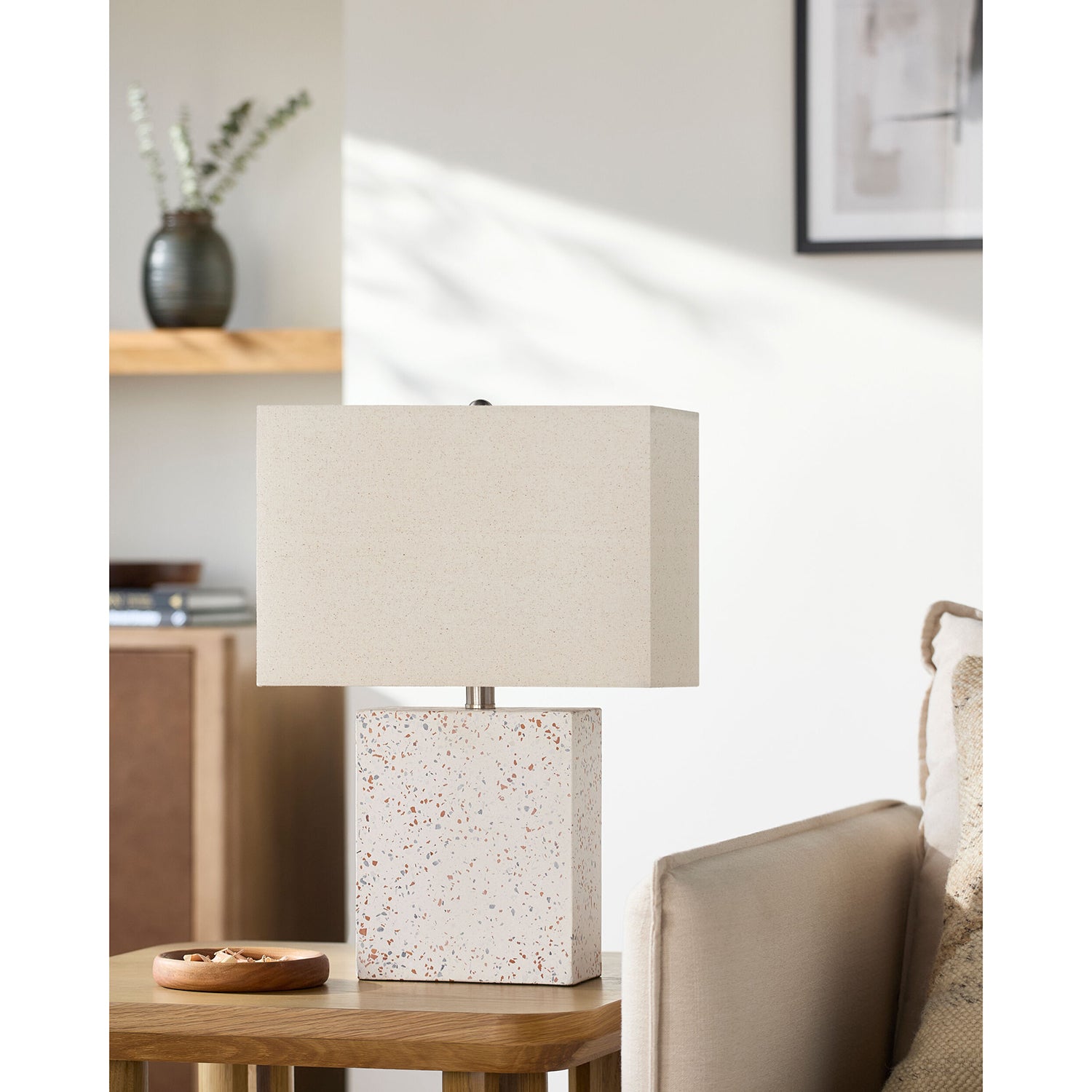 Table lamp with a textured base on a wooden table in a living room setting.