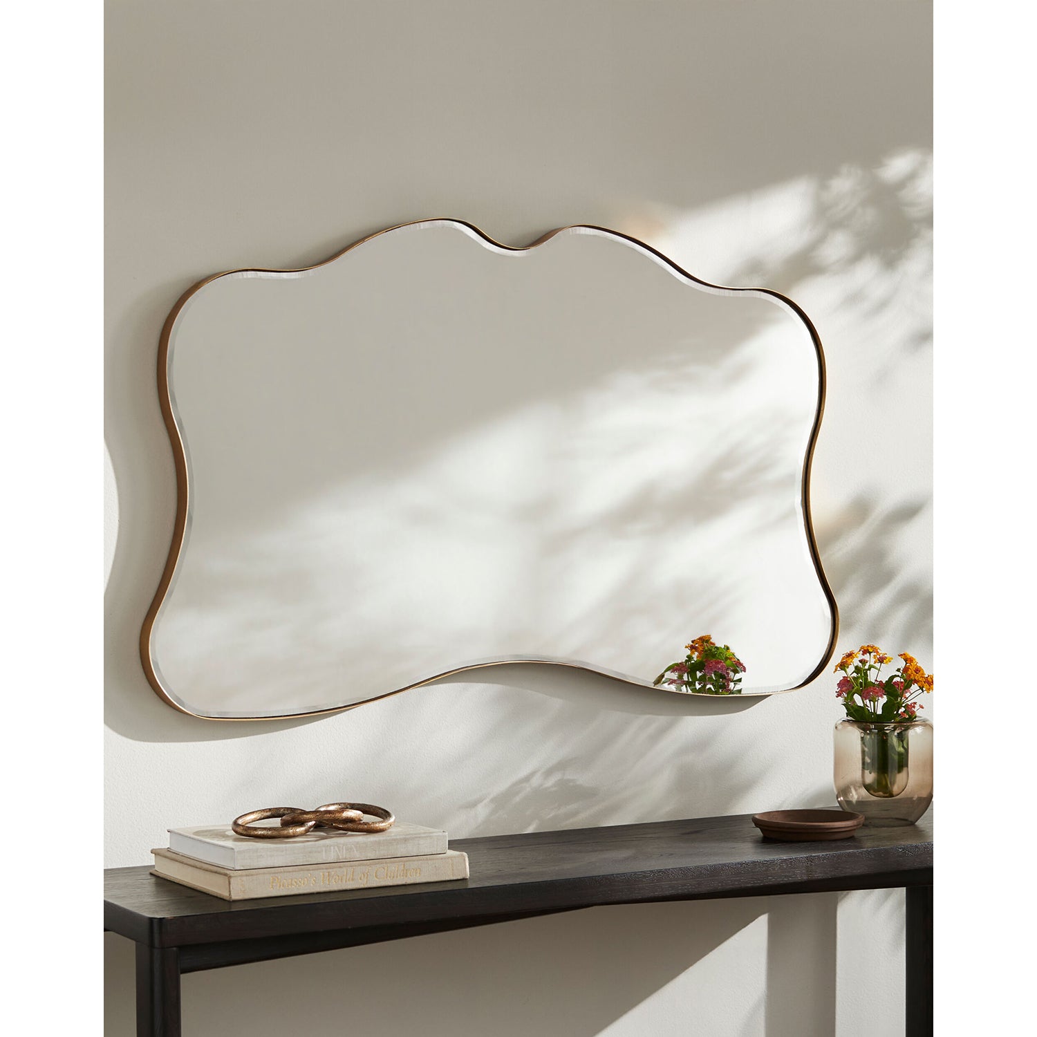 Decorative wall mirror with a wavy frame on a neutral background