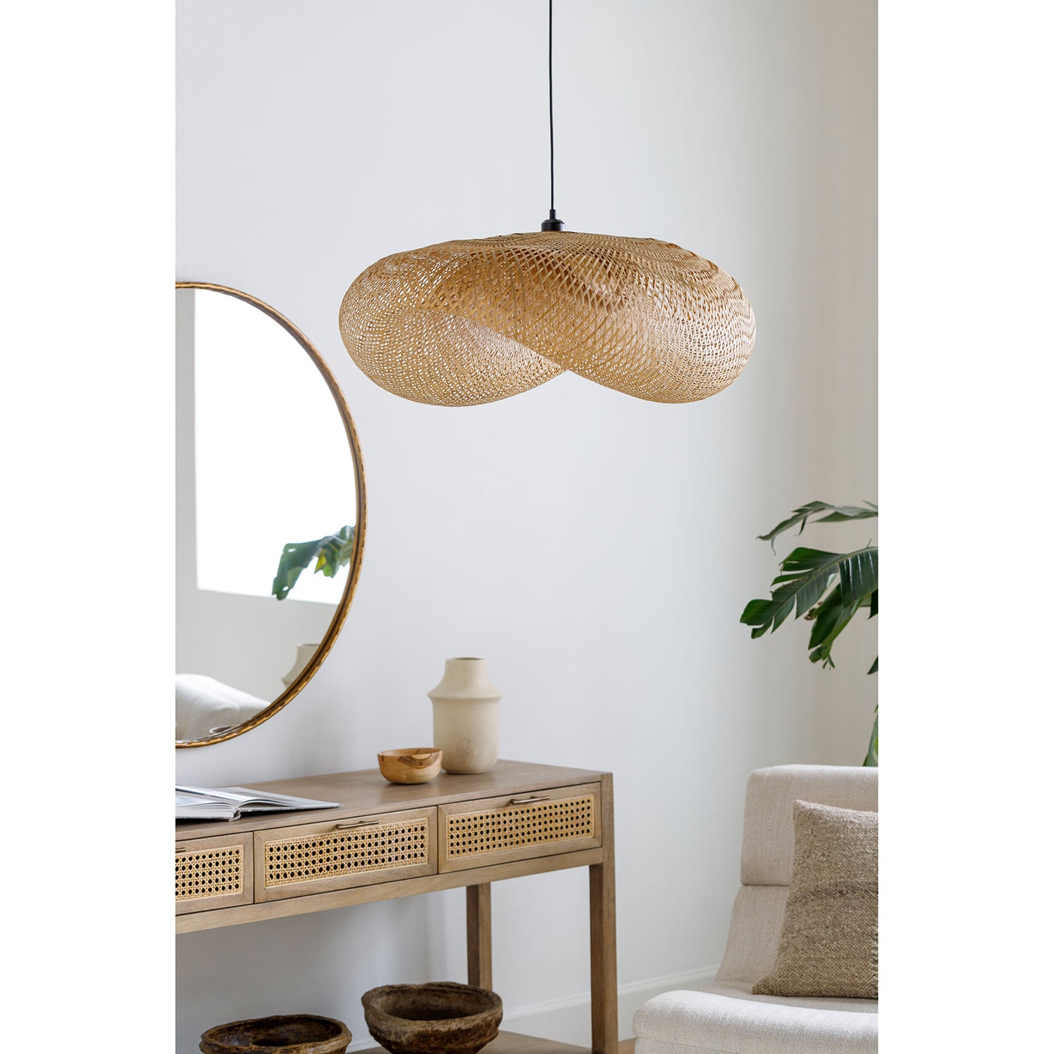 Woven pendant light fixture in a room with a mirror, table, and sofa.