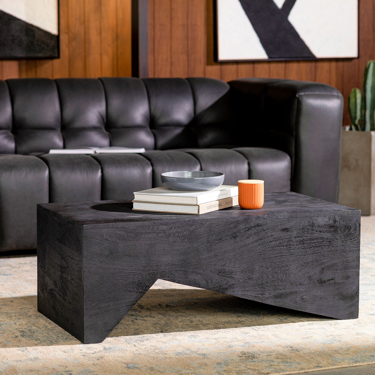 Modern living room with a black leather sofa and a dark wood coffee table.