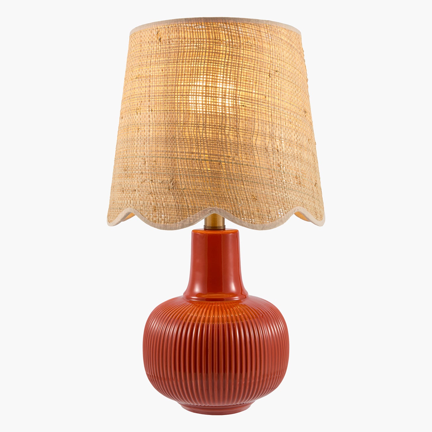 Table lamp with a textured red base and wicker shade on a white background