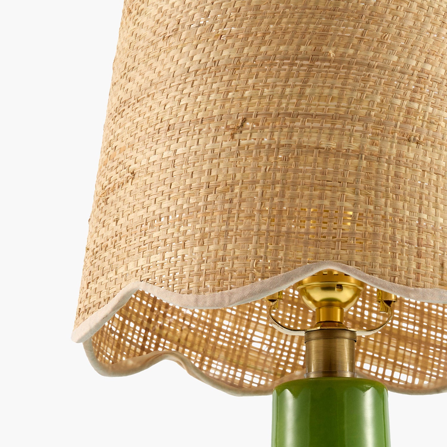 Close-up of a lamp with a woven shade and green base on a white background