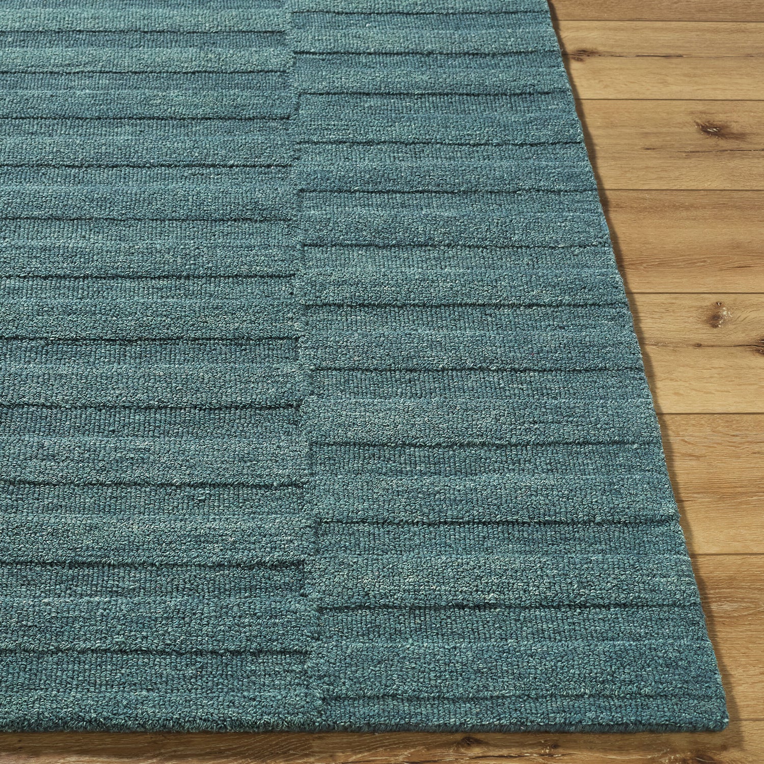 Teal rug with striped pattern on a wooden floor