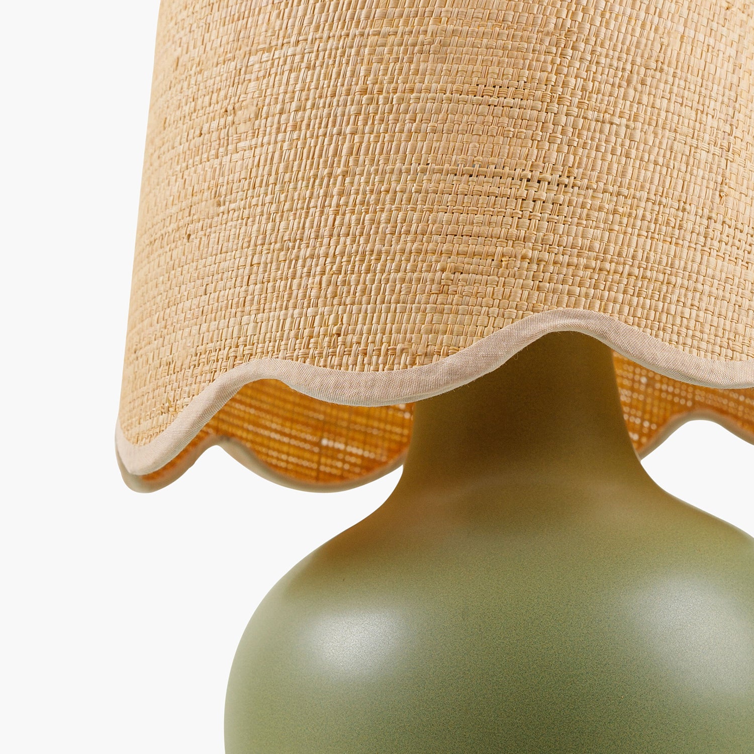 Close-up of a lamp with a textured beige shade and green base on a white background