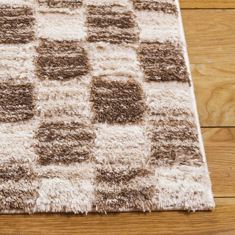 A shaggy area rug with a geometric pattern in ivory and brown tones.