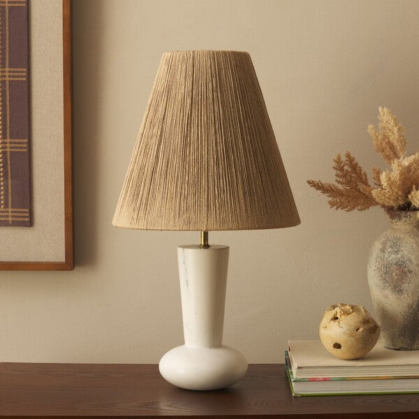 Table lamp with a pleated brown shade on a wooden surface, with decorative items in the background.