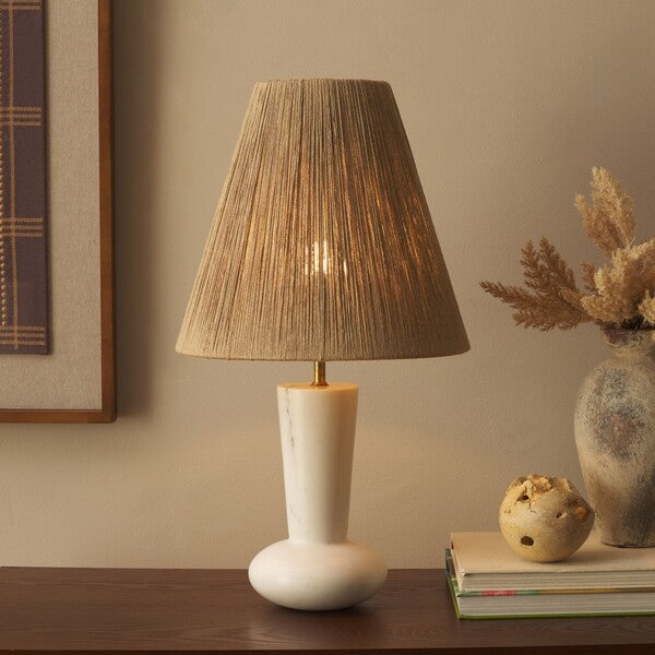 Table lamp with a textured brown shade on a wooden surface, with decorative items in the background.