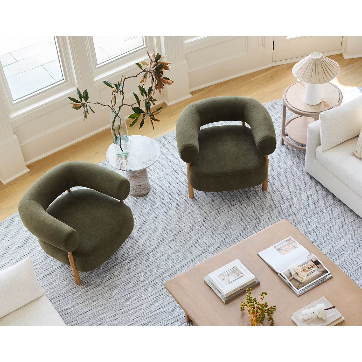 Modern living room with two green armchairs, a coffee table, and decorative items.