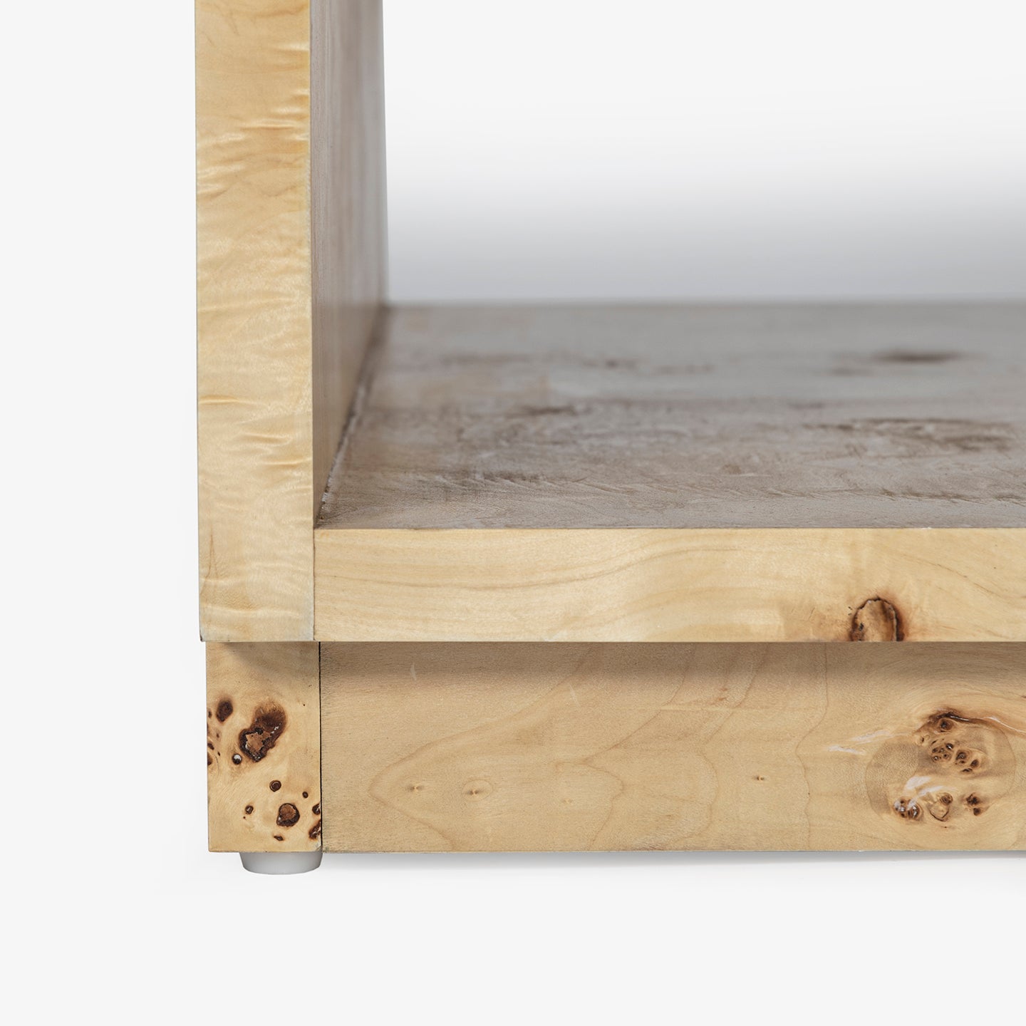 Close-up of a wooden shelf of a coffee table with a light burl finish on a white background