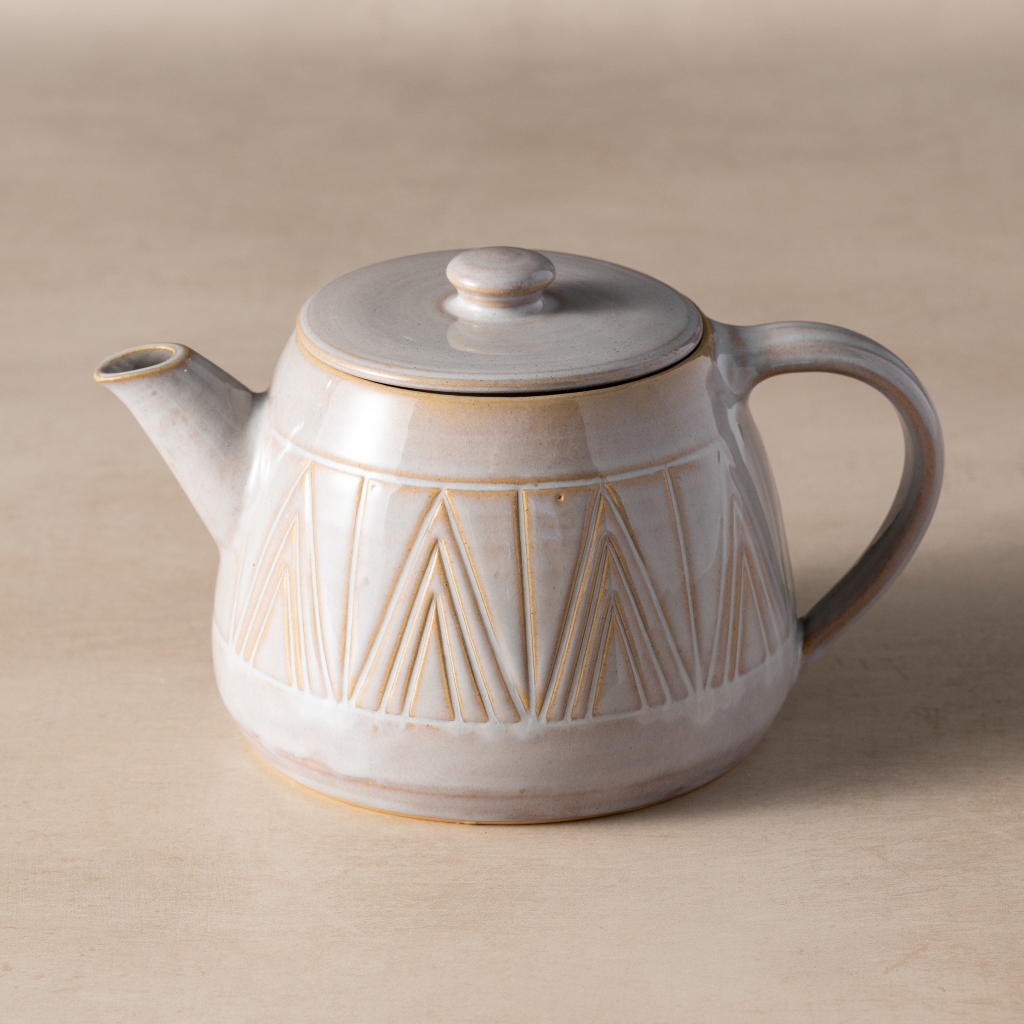 Ceramic teapot with geometric design on a beige background
