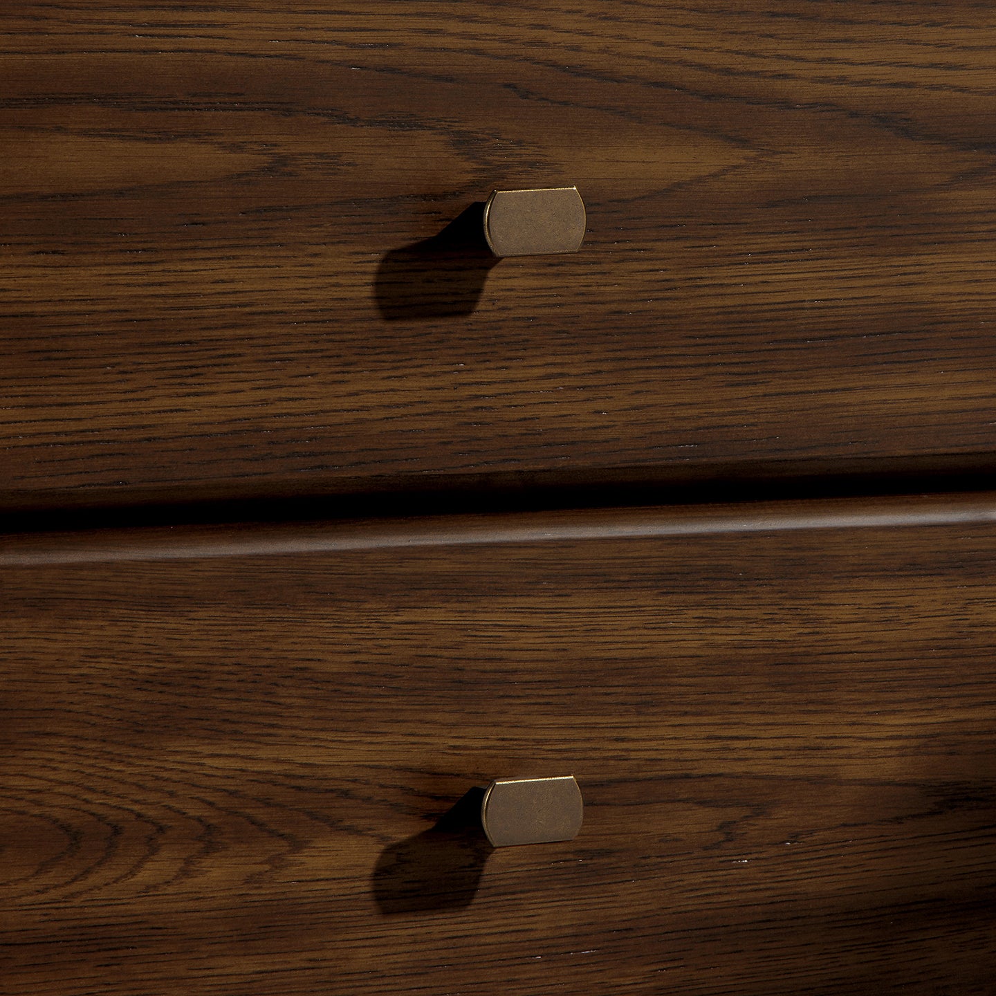 Wooden drawer with brass handles on a dark wood background
